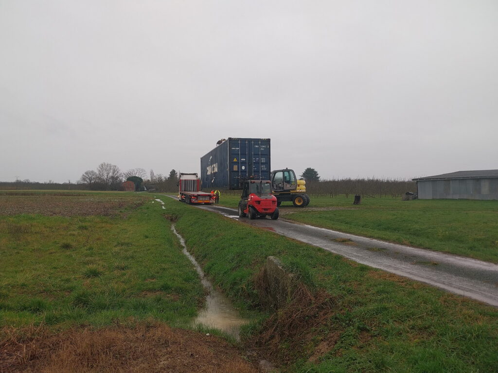 Déchargement avec chariot élévateur du camion plateau d'un conteneur maritime cubner