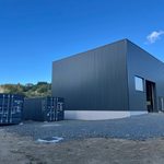 Deux conteneurs 20 pieds RAL 7016 gris anthracite posés devant un bâtiment à bardage bac acier assorti à Saint-Anthème