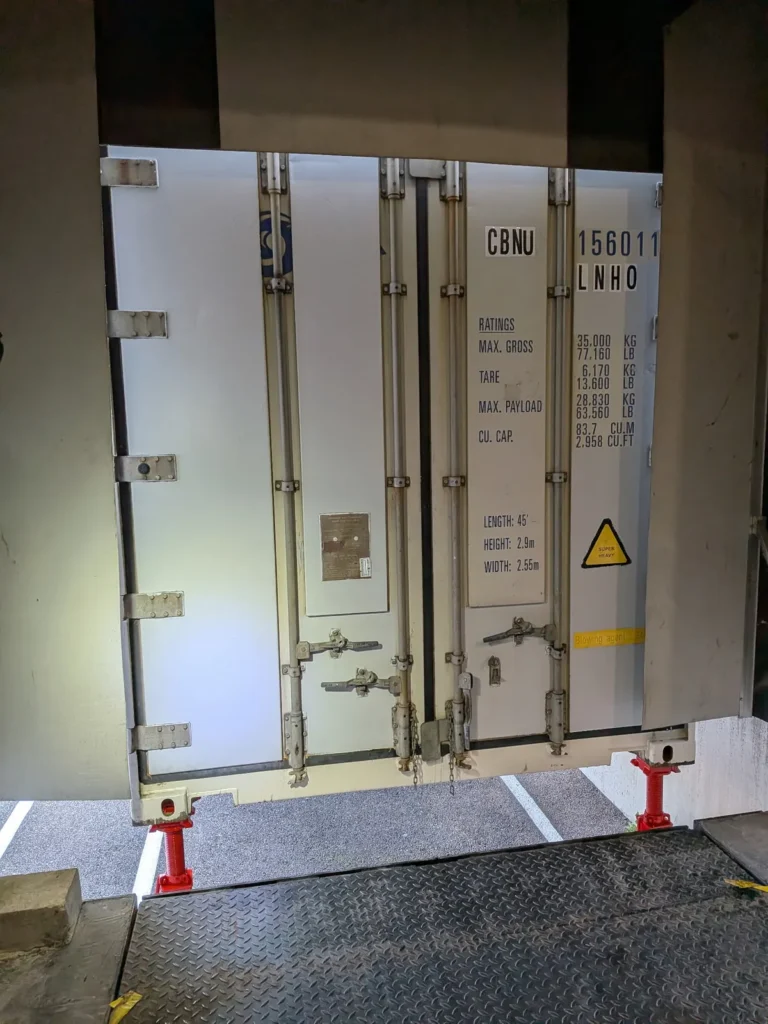 Portes d'un conteneur isotherme 45 pieds alignées à hauteur de quai, vues depuis le niveleur du bâtiment